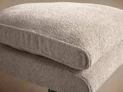 Giorgio Ottoman: Two stacked rectangular cushions in light fawn textured fabric on a brushed metal star base, on a wooden floor.