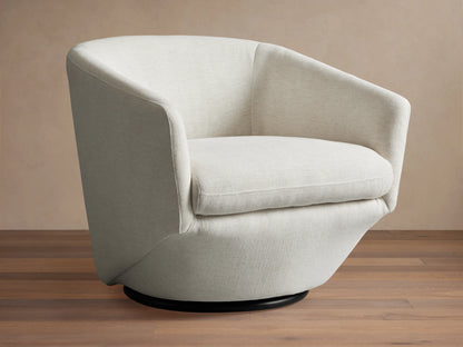 Swivel chair with light beige fabric, curved armrests, cushioned seat and backrest on a black circular base, sitting on wood floor.