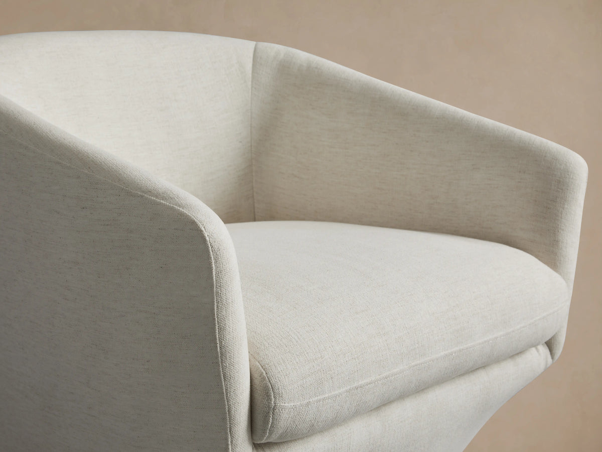 A white Pelton Swivel Chair with a round, cushioned seat and backrest on a black, circular swivel base, set on a wooden floor.