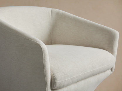 A white Pelton Swivel Chair with a round, cushioned seat and backrest on a black, circular swivel base, set on a wooden floor.