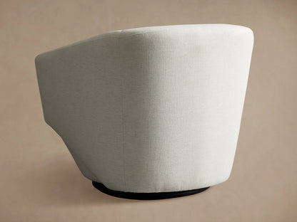 The Pelton Swivel Chair features a light grey fabric with a curved backrest and sleek design on a black swivel base.