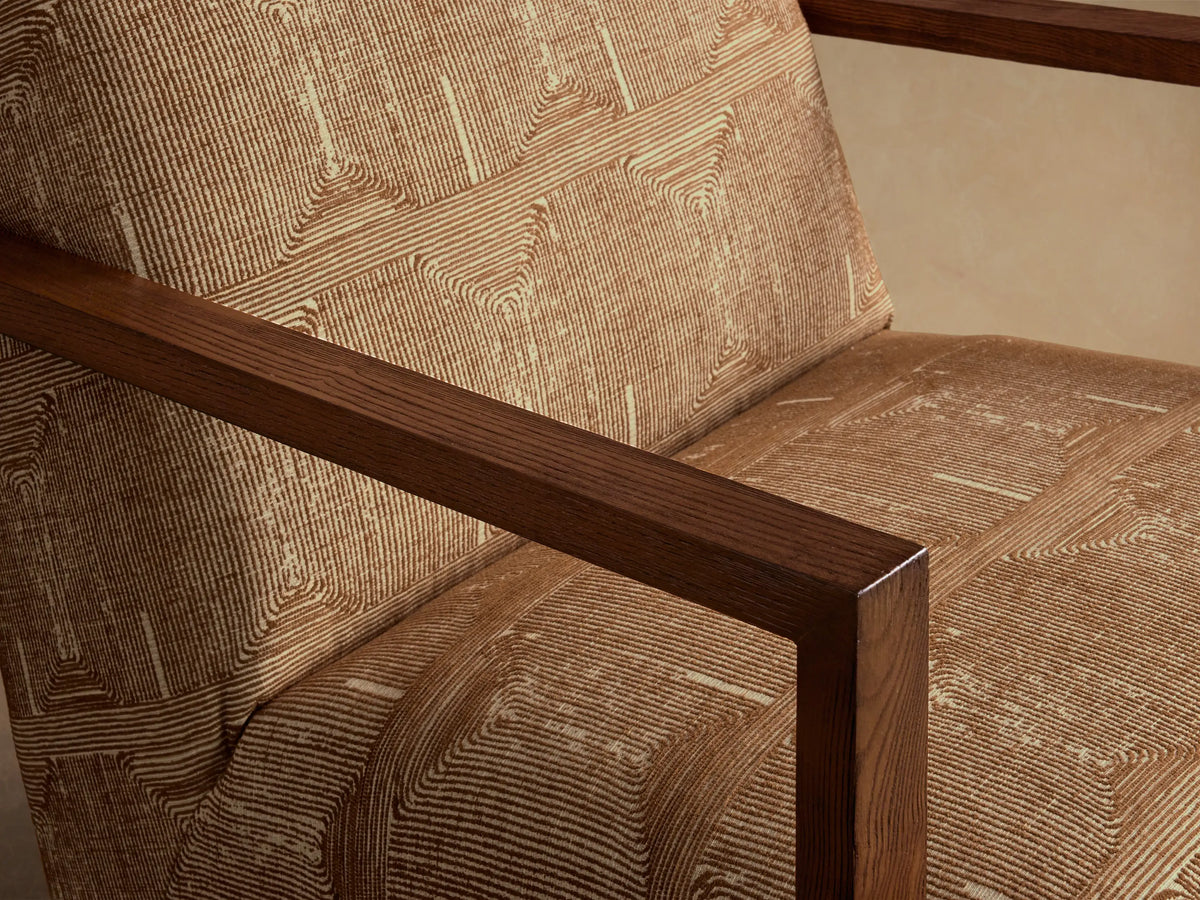 Front view of a tan Walsh Swivel Glider upholstered in cream geometric linear patterned fabric, with dark wood armrests.