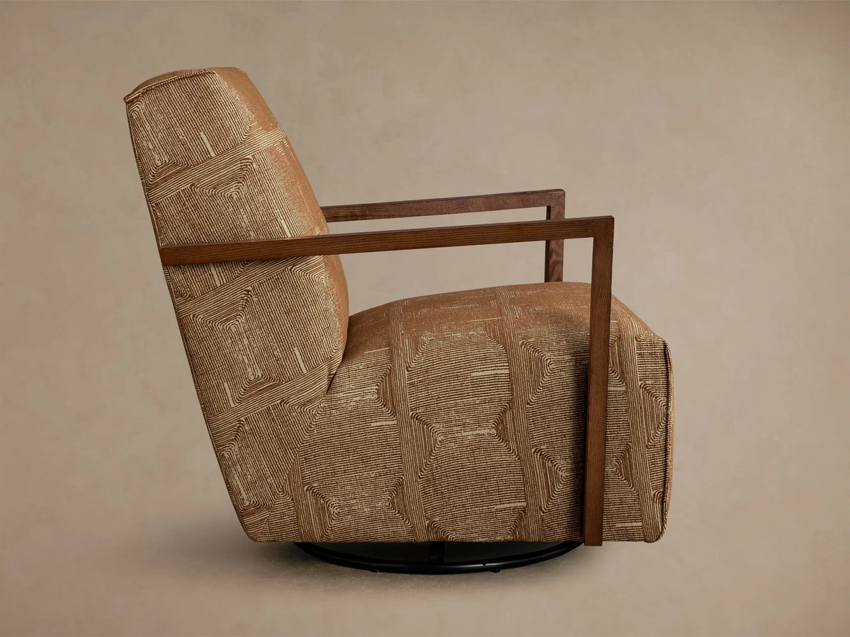 Rear-side view of the brown Walsh Swivel Glider, upholstered in a cream geometric line pattern, with dark wood armrests and a black swivel base.