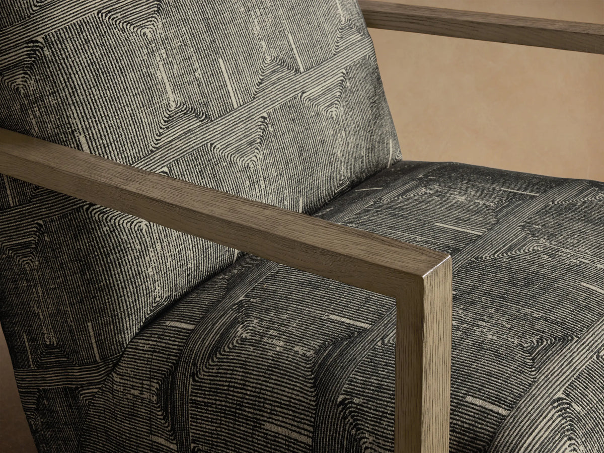 Front view of the Walsh Swivel Glider with black and off-white geometric pattern upholstery and light gray wooden armrests.