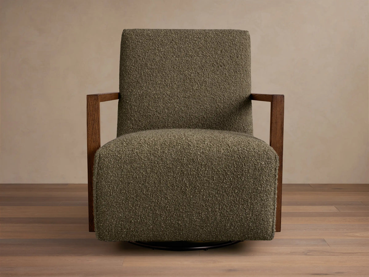 Front three-quarter view of a green textured Walsh Swivel Glider with dark wood L-shaped armrests and a black swivel base.