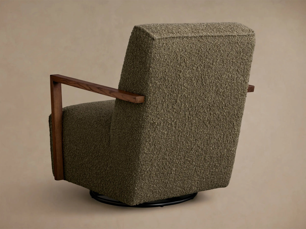 Close-up of the moss green bouclv© fabric and dark wood armrest on the Walsh Swivel Glider.