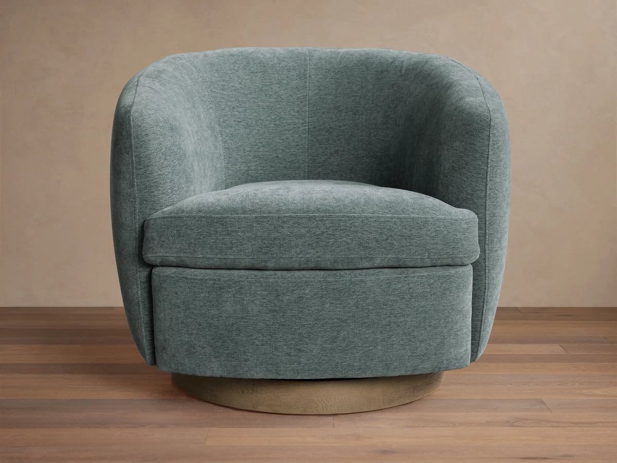 Cerrito Swivel Chair, round barrel-shaped with dusty teal fabric upholstery, single seat cushion, and a light wood swivel base.
