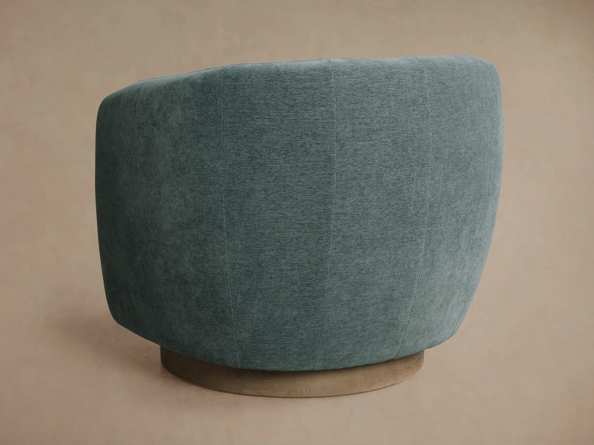 Cerrito Swivel Chair: rounded, upholstered in textured teal fabric, shown in profile on a light wood circular swivel base.