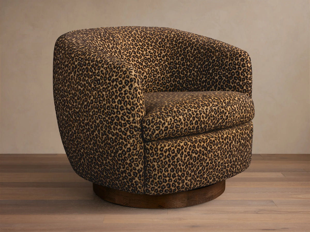 Front-right view of the brown leopard print Cerrito Swivel Chair, featuring a rounded barrel shape and a dark wood swivel base.