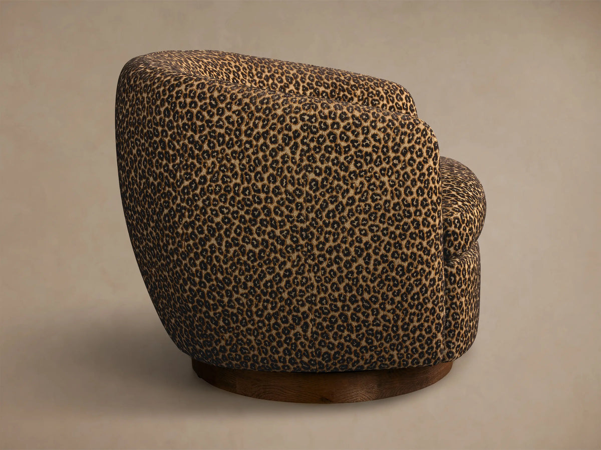 Side view of the Cerrito Swivel Chair, upholstered in brown and black leopard print fabric with a round dark wooden base.