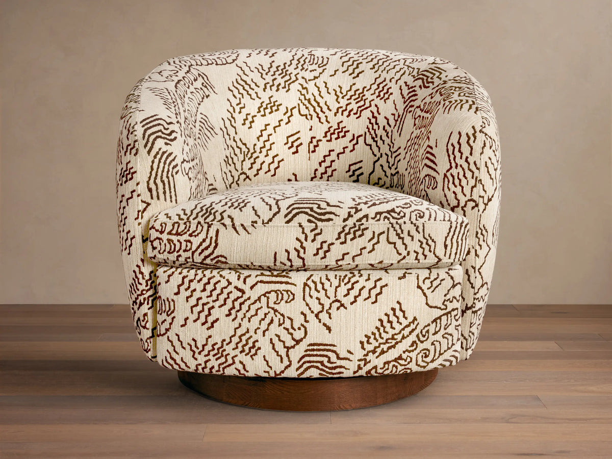 Front view of the Cerrito Swivel Chair, upholstered in cream fabric with a dark brown abstract organic pattern, on a dark wood swivel base.