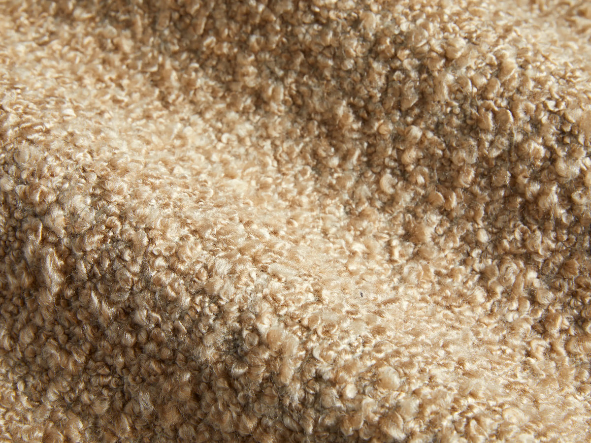 Side profile of a beige textured boucle Cerrito Swivel Chair with a dark wooden swivel base.