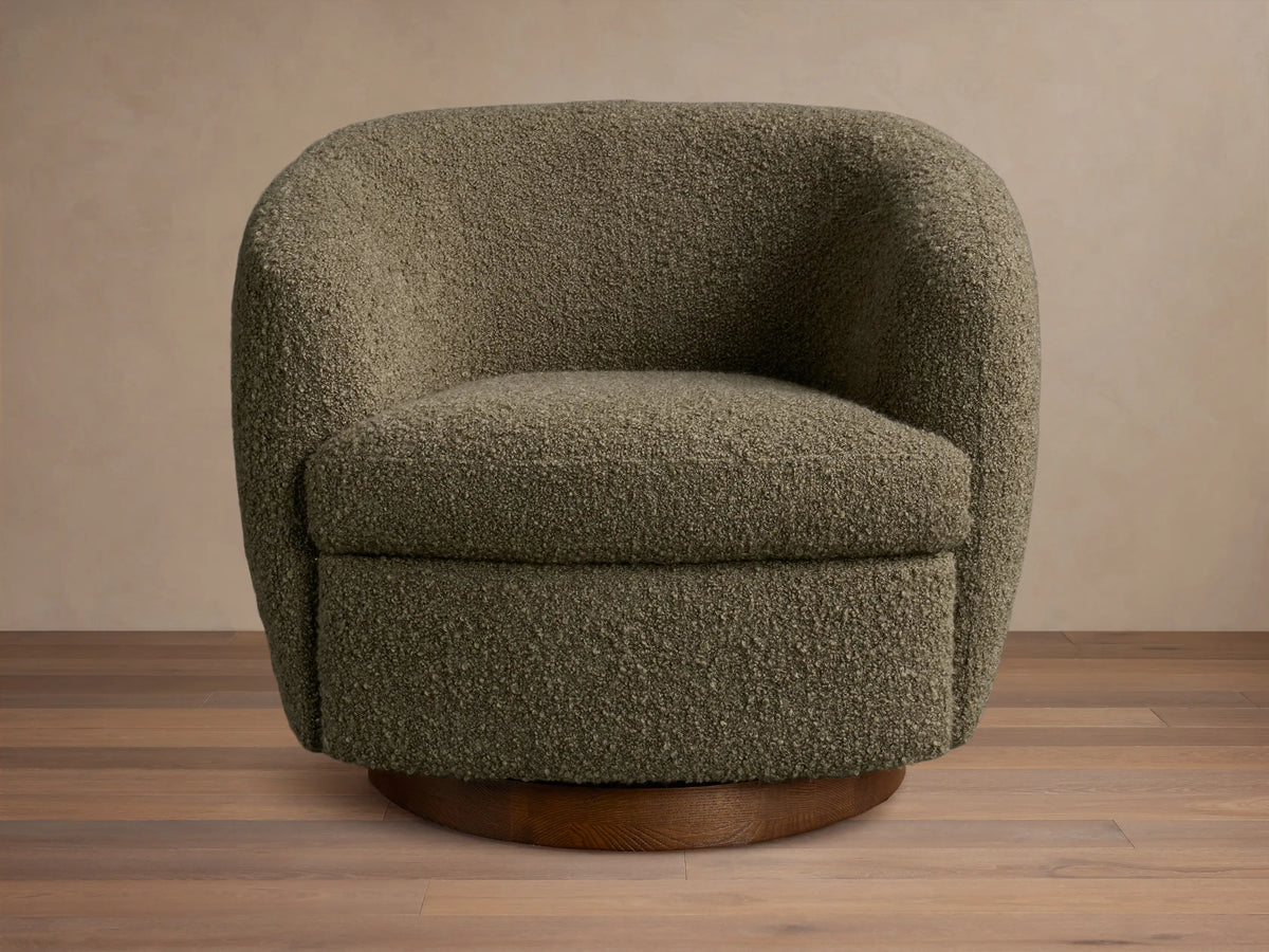 Front view of an olive green bouclv© Cerrito Swivel Chair with a rounded silhouette and a dark wooden swivel base.