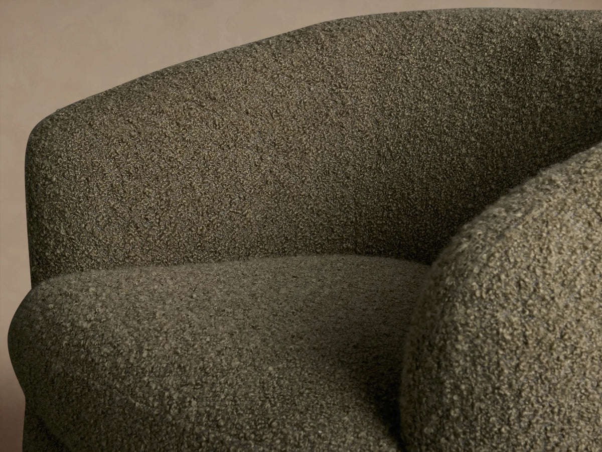 Front view of an olive green Cerrito Swivel Chair with rounded silhouette, bouclv© upholstery, and a dark wooden swivel base.
