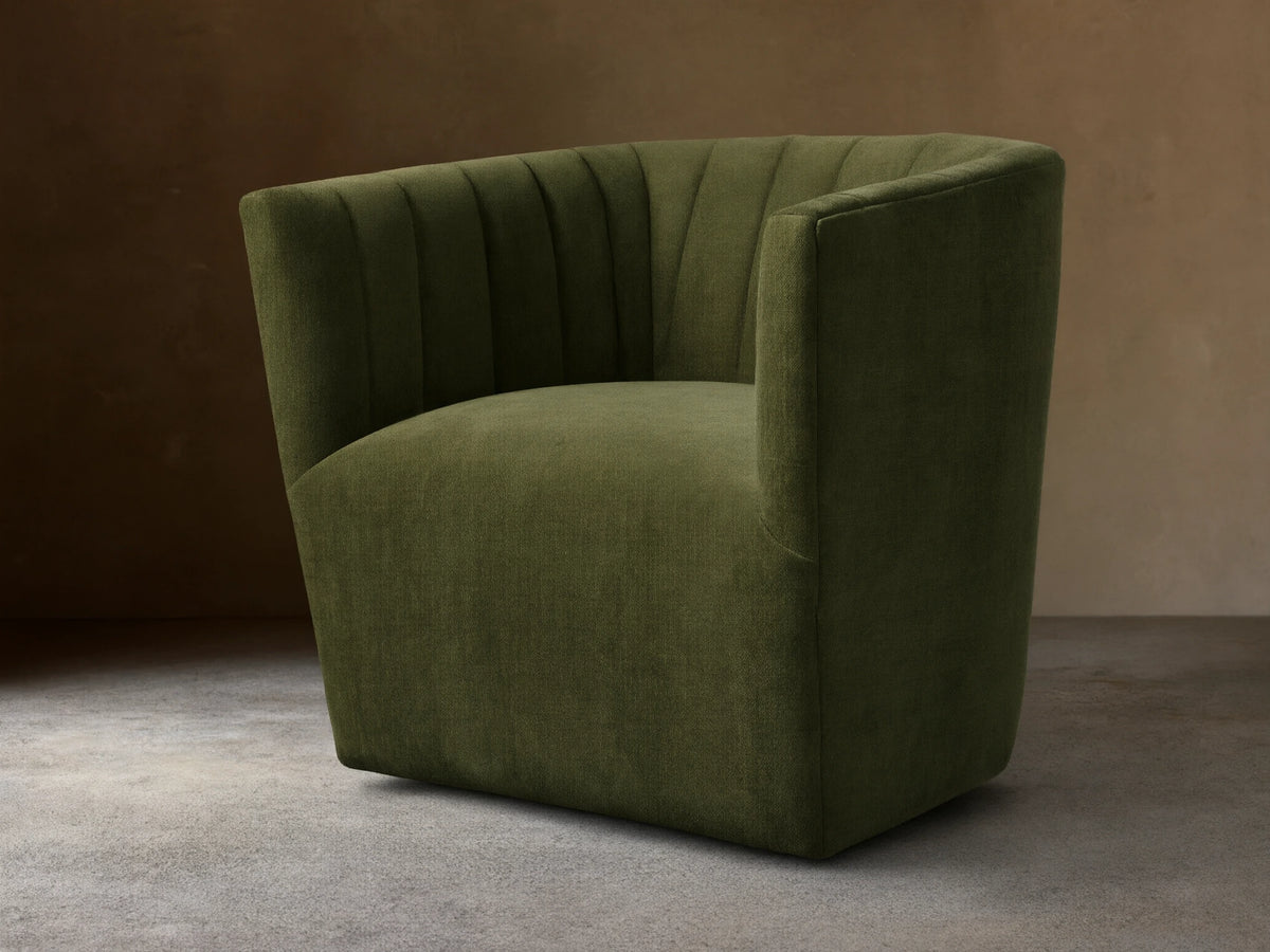 Green Griffin Swivel Chair with a rounded back and vertical channel tufting, set on a wooden floor.