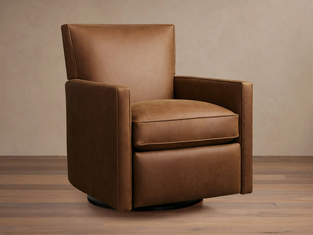 Rudy Leather Swivel Recliner in brown leather, featuring cushioned seat and backrest, square arms, and swivel base on wooden floor.