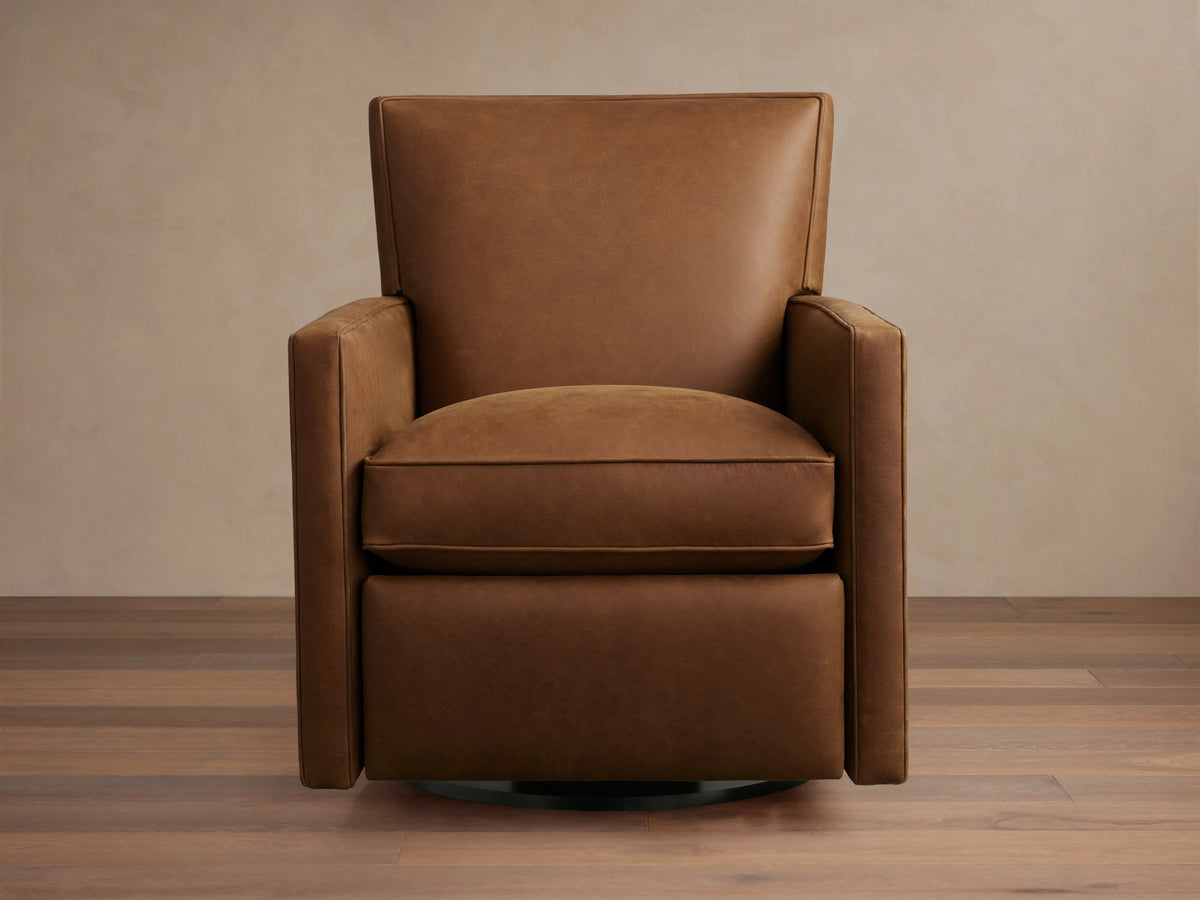 Rudy Leather Swivel Recliner in brown leather, featuring cushioned seat and backrest, square arms, and swivel base on wooden floor.
