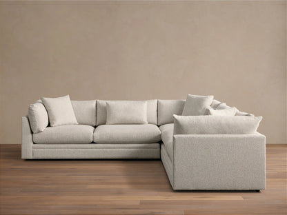 Light grey textured Pavo Three Piece Corner Sectional sofa, L-shaped, with multiple cushions, on a wood floor.