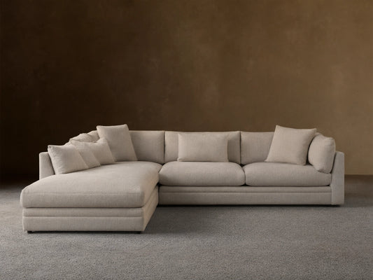 Light grey textured Pavo Three Piece Corner Sectional sofa, L-shaped, with multiple cushions, on a wood floor.