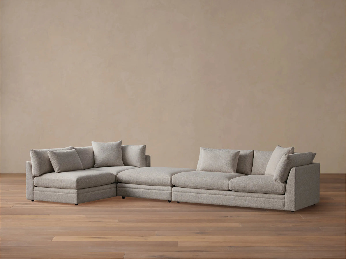Pavo Three-Piece Sectional, light beige, L-shaped with a left chaise and multiple soft cushions, on wood floor, tan wall.