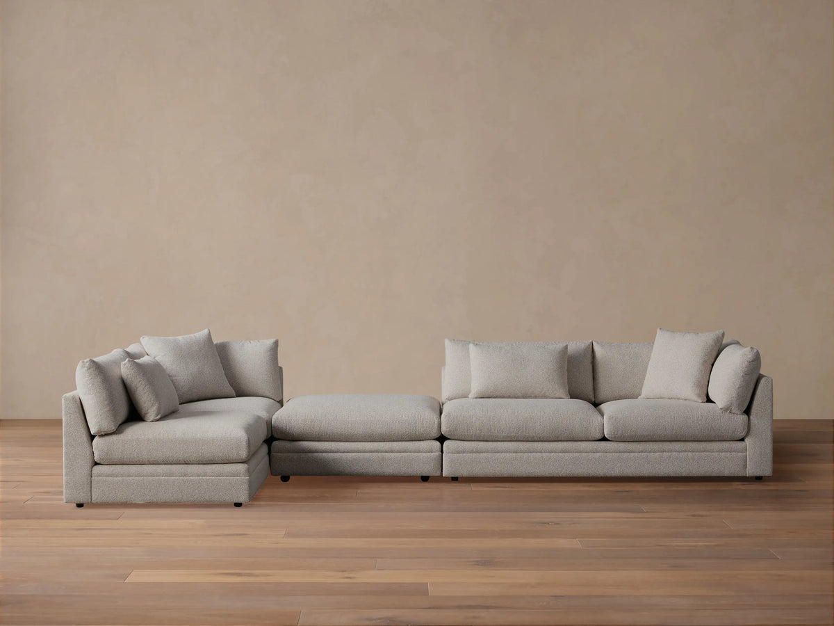 Rear-side view of the light grey Pavo Three-Piece Sectional, showcasing its modular design and textured fabric with back cushions.