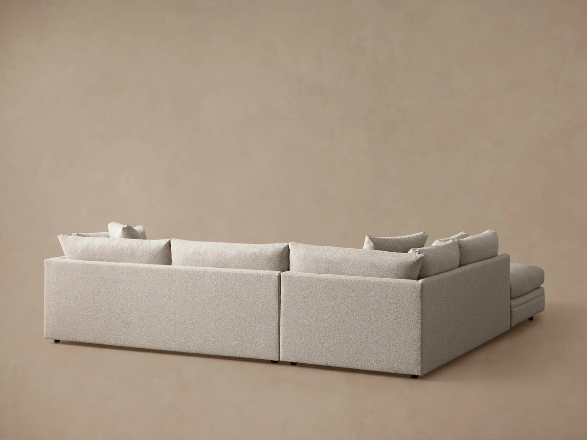 Close-up of light beige Pavo Three-Piece Sectional, textured fabric, plush seat and back cushions, and a throw pillow.