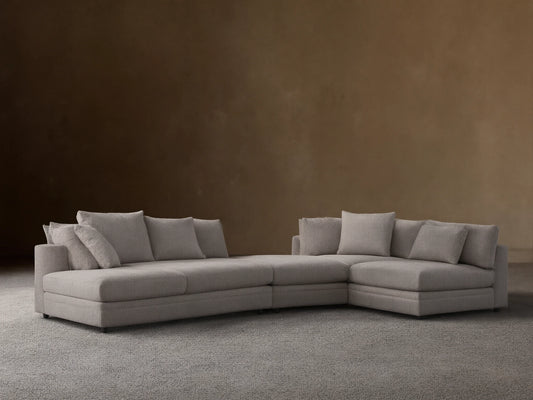 Pavo Three-Piece Sectional, light beige, L-shaped with a left chaise and multiple soft cushions, on wood floor, tan wall.