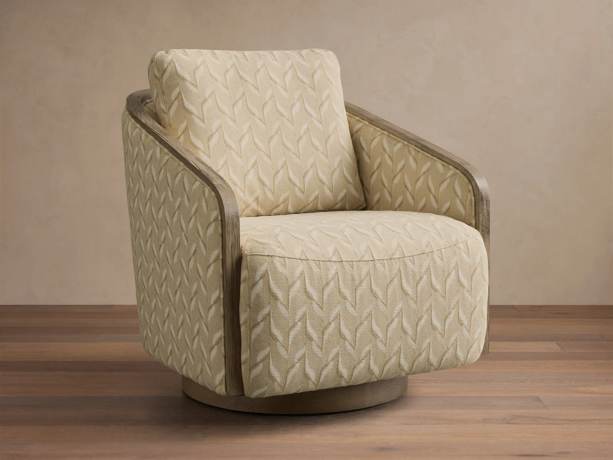 Front view of the beige leaf-patterned Pomona Swivel Chair, with exposed light oak arms and a round swivel base.