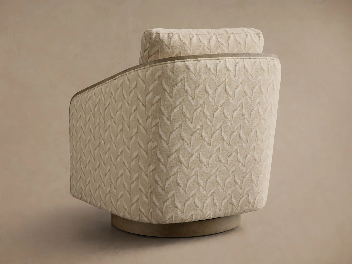 Angled view of the light beige Pomona Swivel Chair with a subtle leaf pattern, featuring curved exposed oak armrests.