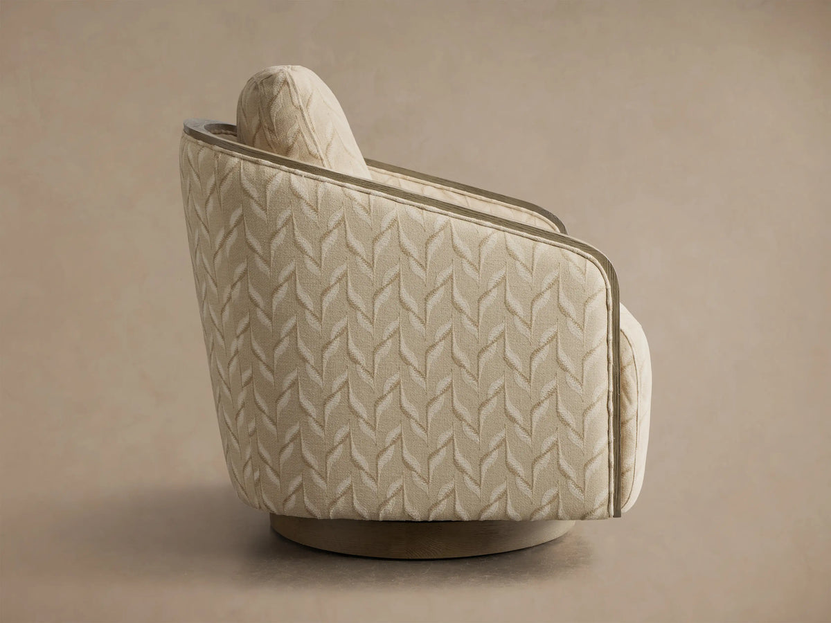 Rear view of the light beige Pomona Swivel Chair, featuring a subtle leaf pattern, exposed oak arm edges, and a round wooden swivel base.