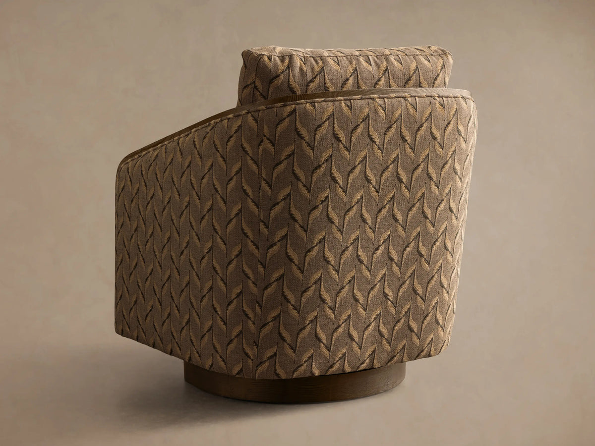 Close-up of the Pomona Swivel Chair, upholstered in taupe fabric with a beige and dark brown leaf pattern, dark oak frame.