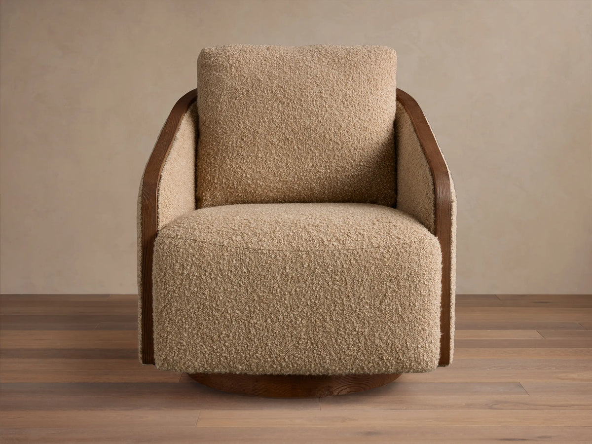 Front 3/4 view of the Pomona Swivel Chair with neutral cushions and exposed oak arms, featuring a wooden swivel base.