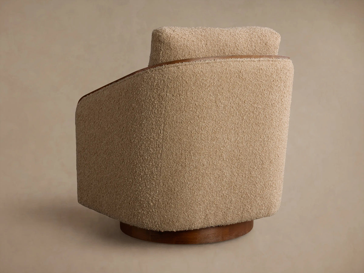 Close-up of the beige Pomona Swivel Chair's Crypton¬Æ Nomad Snow bouclv© fabric and exposed oak armrests.