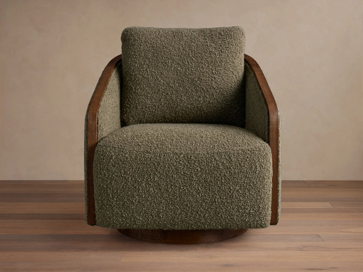 Front-side view of a neutral beige Pomona Swivel Chair with exposed dark oak edges, sitting on a light rug in a living room.