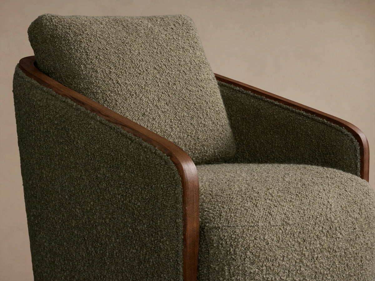 Front view of an olive green bouclv© Pomona Swivel Chair with exposed light brown oak arms and a round wooden swivel base.