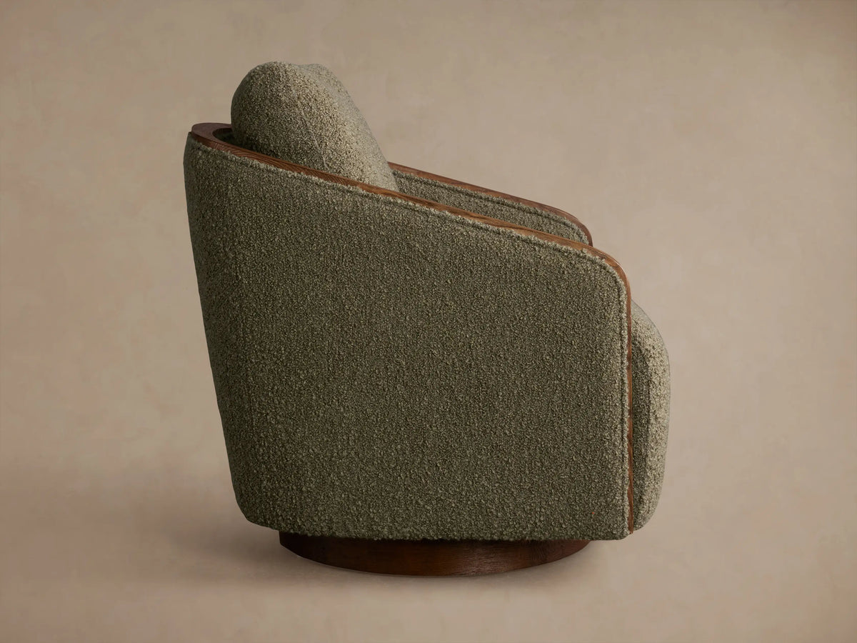 Rear view of the Pomona Swivel Chair, upholstered in olive green textured fabric with exposed oak trim and a wooden swivel base.