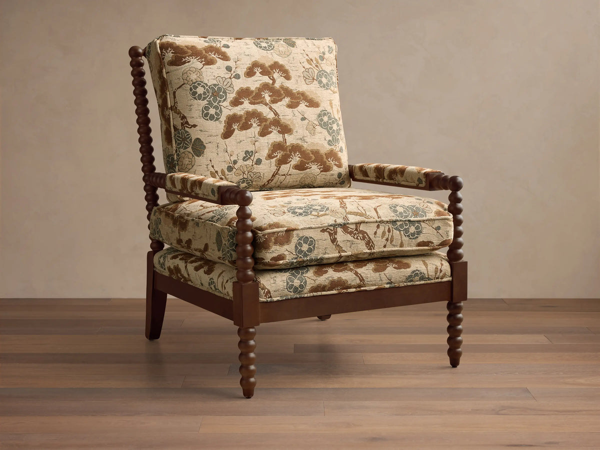 Front view of Milly Chair with dark brown spindled wood frame and beige fabric with brown and teal pine tree pattern.