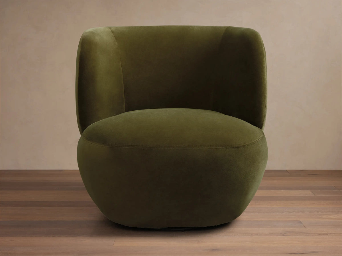 Olive green velvet upholstered chair featuring a deeply curved back and integrated armrests.