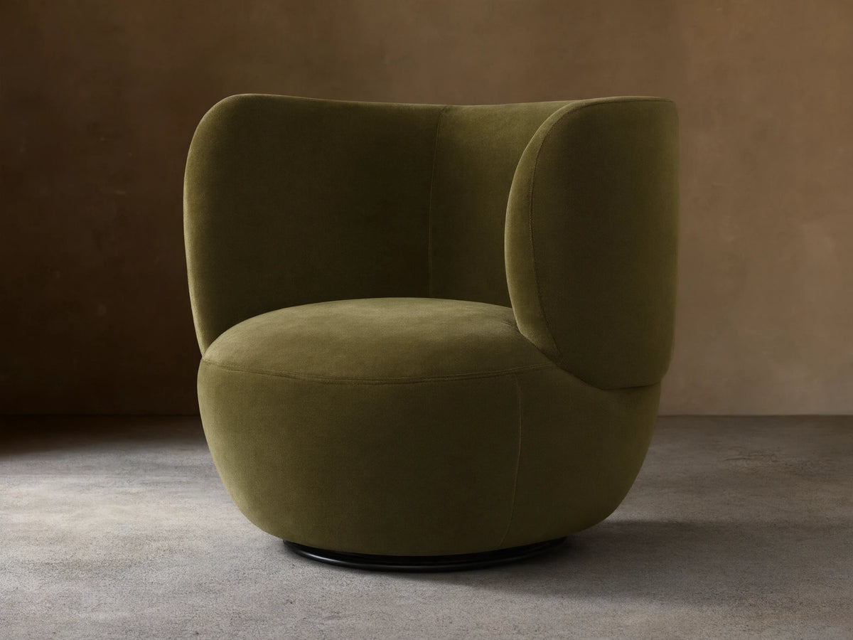 Olive green velvet upholstered chair featuring a deeply curved back and integrated armrests.