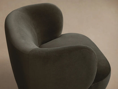 Front view of a dark green velvet armchair with a rounded, sculptural shape and plush texture.