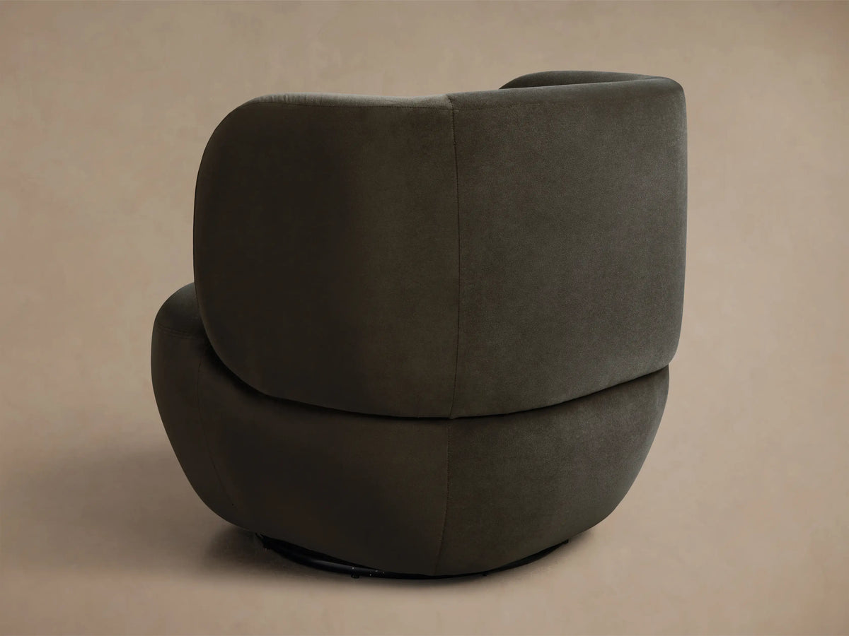 Close-up of dark olive green upholstered chair with curved back and deep, plush seat in soft fabric.