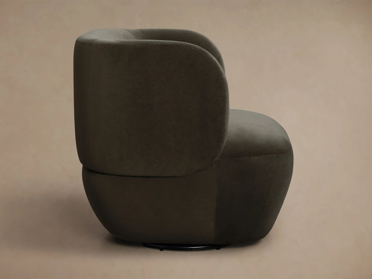 Rear view of a dark gray upholstered modern accent chair with a curved back and seat.