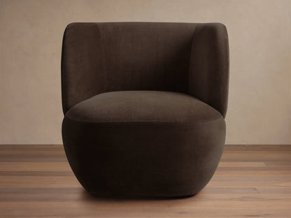 Dark brown Lenny Swivel Chair with plush, rounded backrest and seat, set on a wooden floor. The chair features a seamless, modern design.