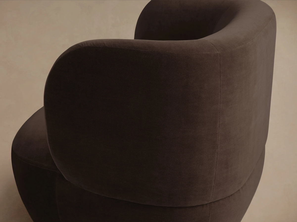 Dark brown Lenny Swivel Chair with a curved backrest and smooth upholstery, shown on a wooden floor, facing forward.