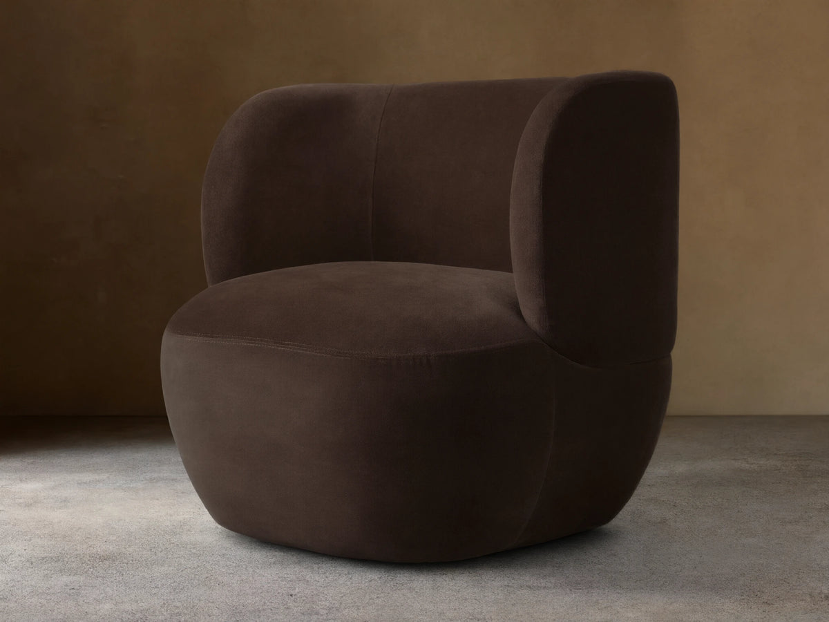 Dark brown Lenny Swivel Chair with plush, rounded backrest and seat, set on a wooden floor. The chair features a seamless, modern design.