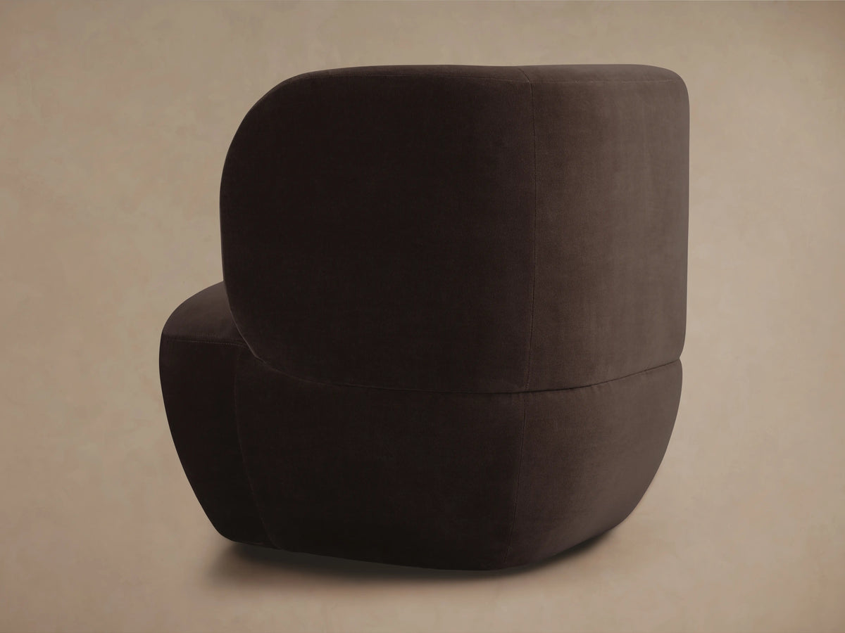 Dark brown Lenny Swivel Chair with a curved, modern design seen in side view. Features plush cushioning and smooth fabric.