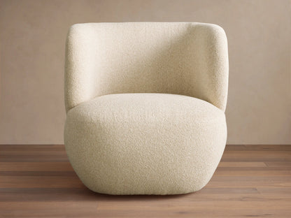 Lenny Swivel Chair, modern, full-bodied, light cream textured fabric with curved back and arms, on a wooden floor.