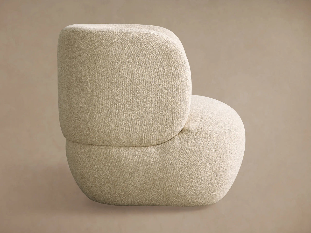 Back view of the Lenny Swivel Chair; a plush, rounded, light beige textured chair with a distinctive curved form.