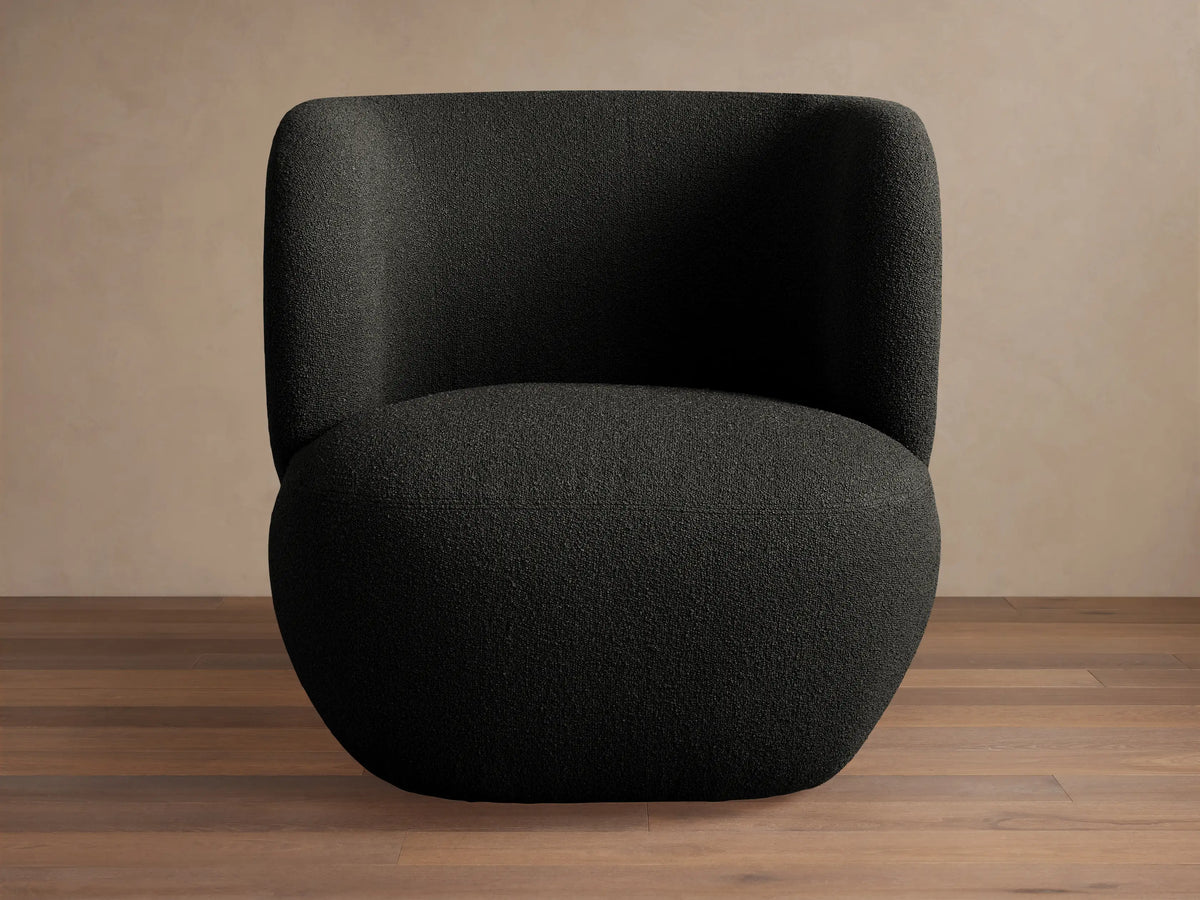 Lenny Swivel Chair: Modern, dark gray/black textured boucle fabric. Curved, armless design, front-right view on a wood floor.