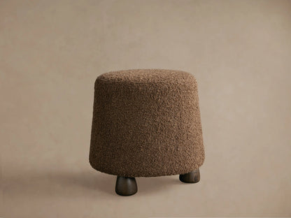 Steffi Ottoman close-up, showing its rich brown, deeply textured bouclé fabric covering the curved top and side.